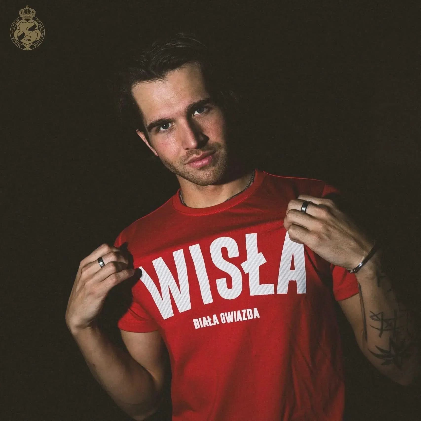 Man wearing a red 'Wisła' t-shirt against a dark background