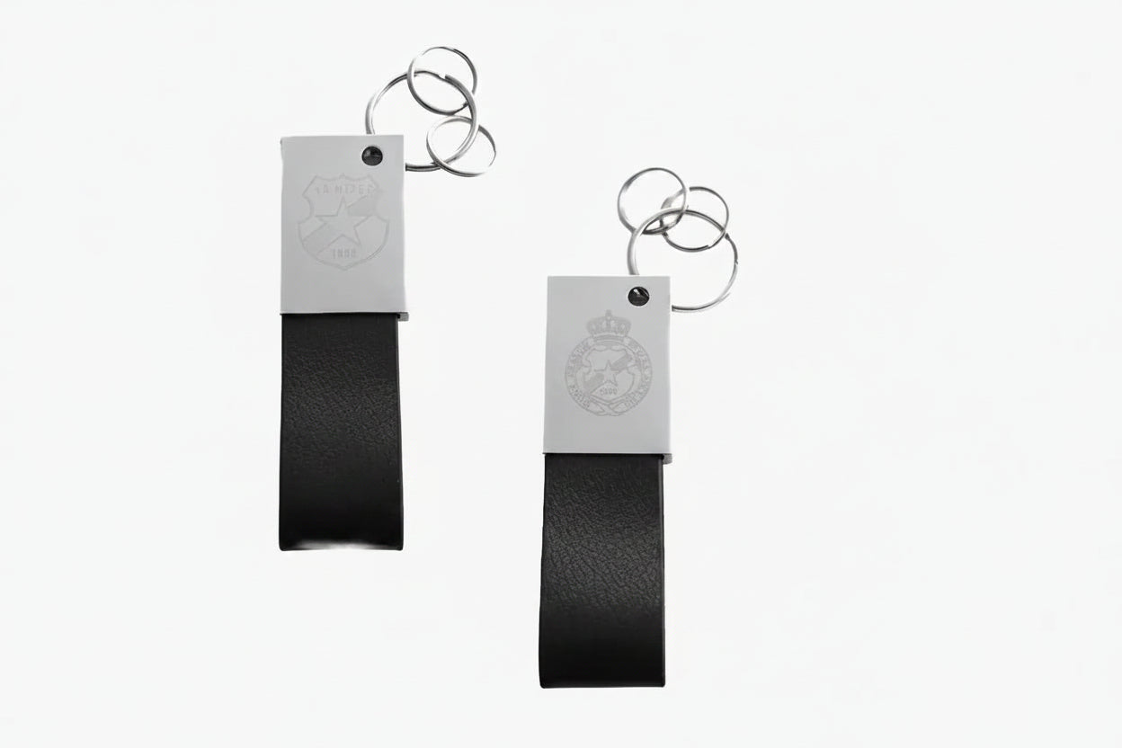 Two black leather keychains with metal tags on a white background